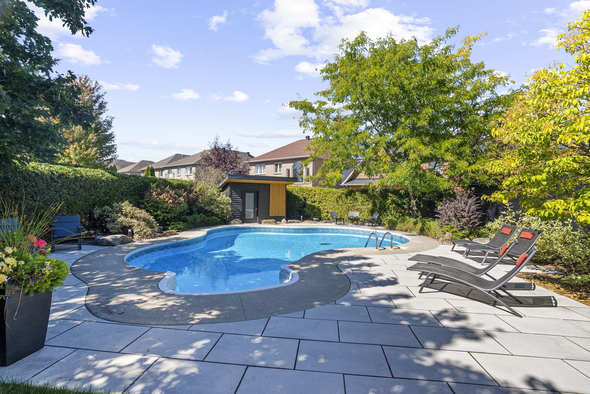 Freeform pool framed by mature planting and a tucked-in cabana.