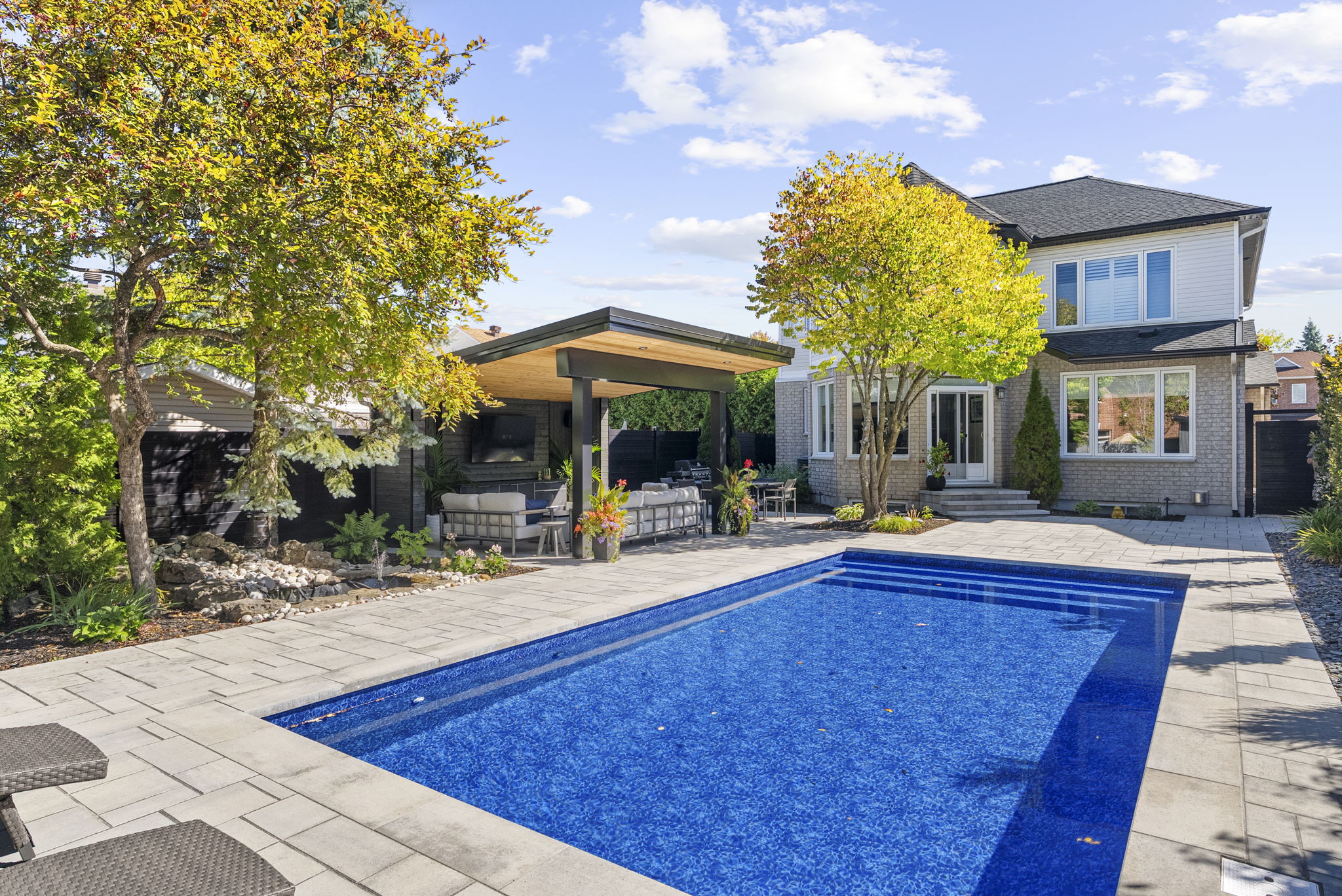Rectangular backyard pool with a covered cabana and surrounding hardscape.