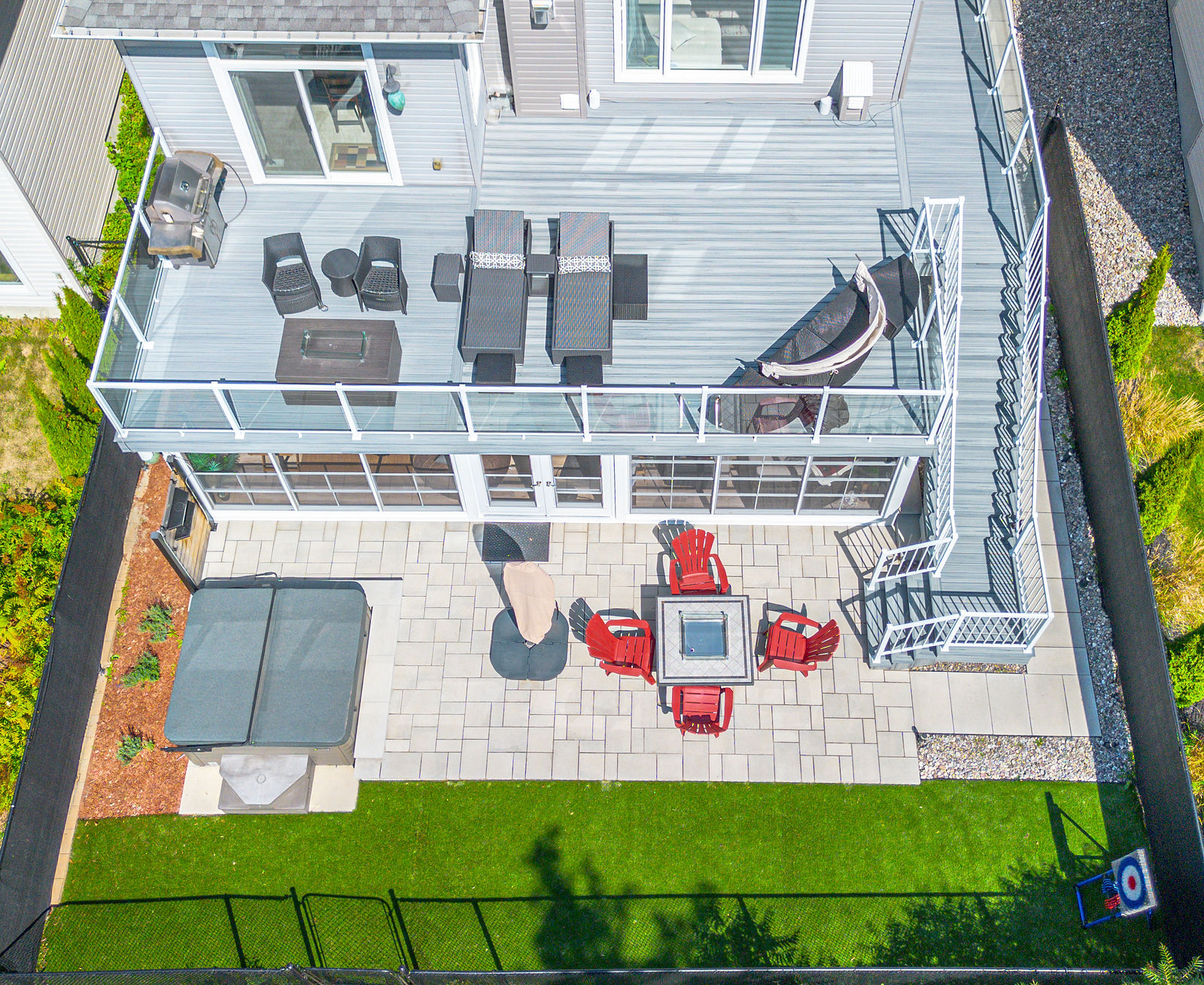 Elevated composite deck with a hot tub and lower terrace.