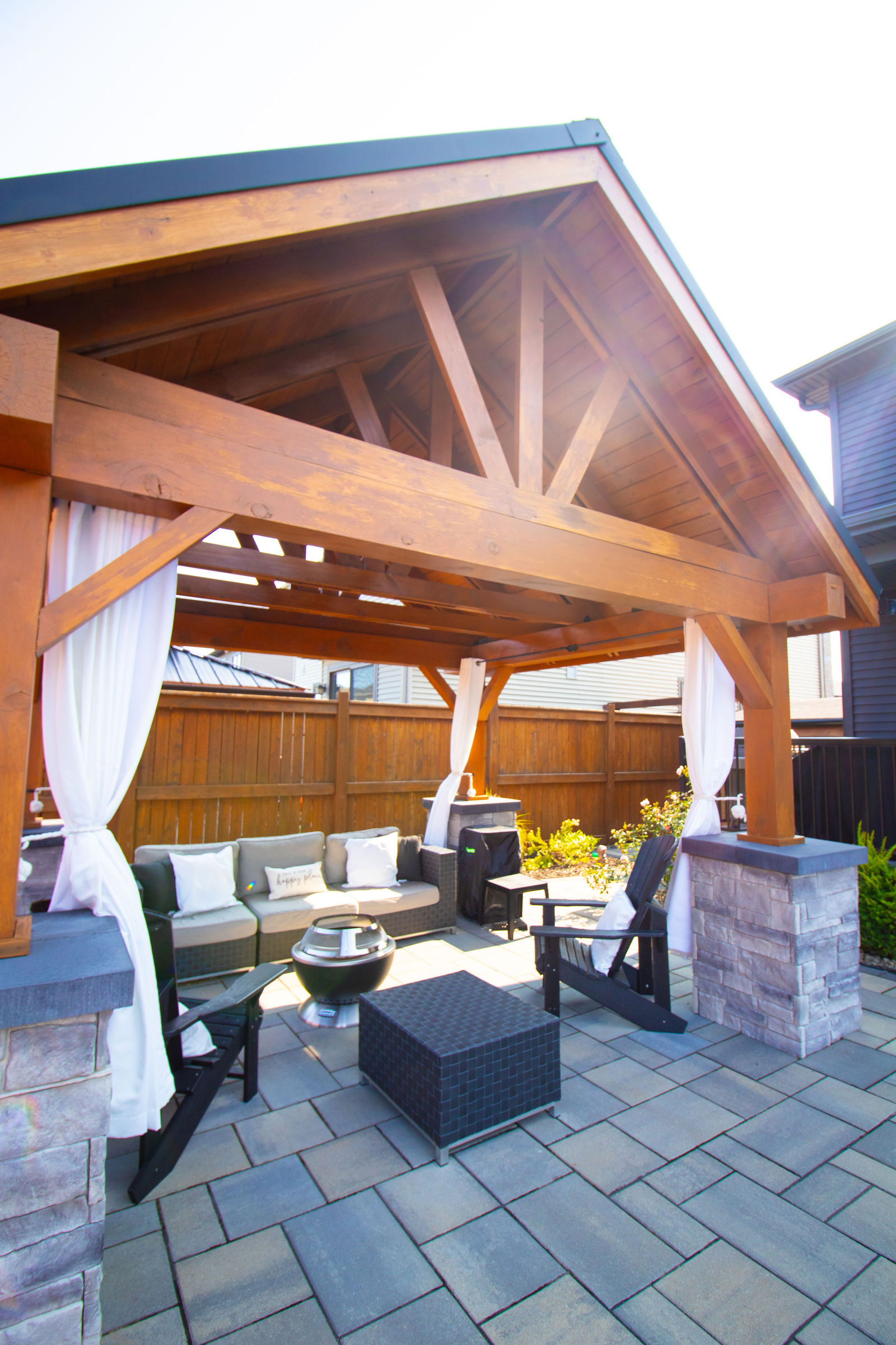 Timber pavilion with exposed wood structure, drapery, and built-in lounge seating.