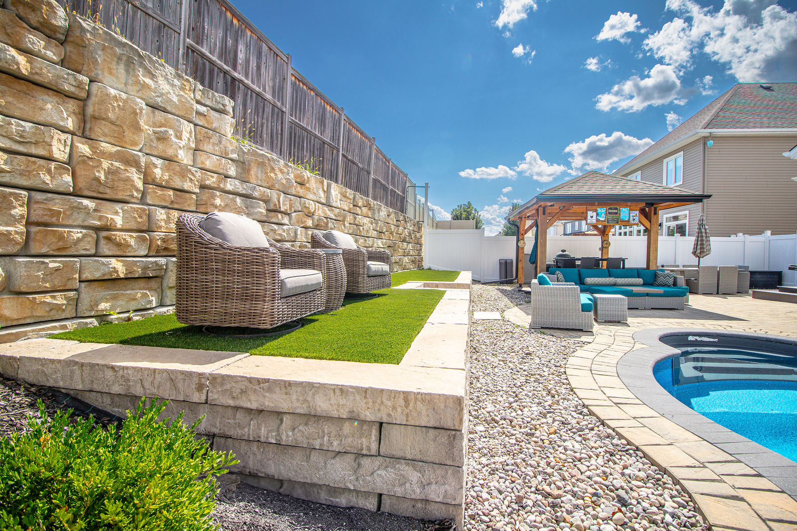 Retaining wall, stone steps, and integrated hardscape seating within a finished backyard build.