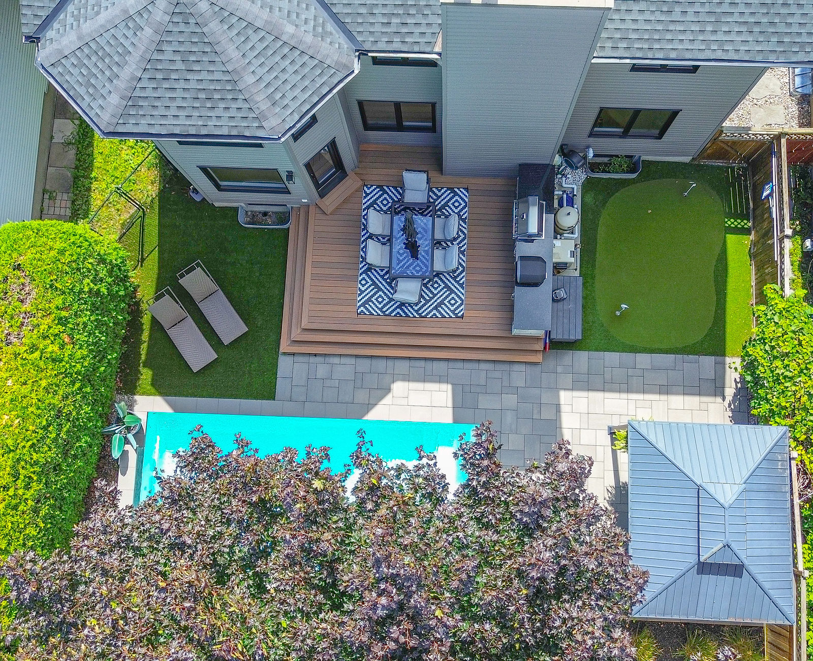 Modern pool patio with an outdoor kitchen and integrated hardscape.