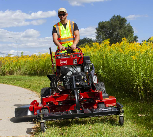 Toro stand-on mower cutting a maintained turf edge during commercial lawn service.